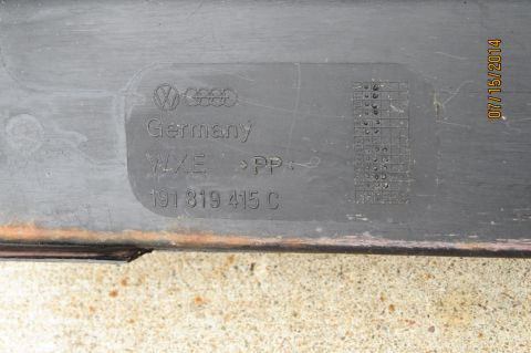 1985 Volkswagen Jetta - A black plastic Volkswagen part is shown with manufacturing details and a part number stamped into its surface.