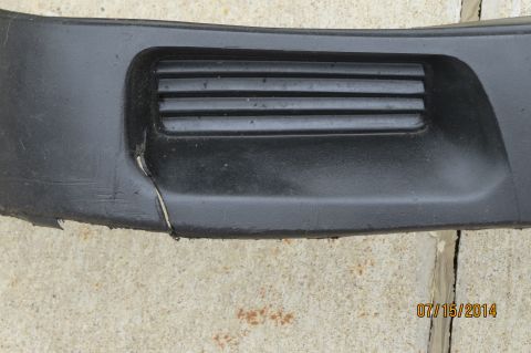1985 Volkswagen Jetta - A cracked black car bumper with a vent is shown against a concrete surface.