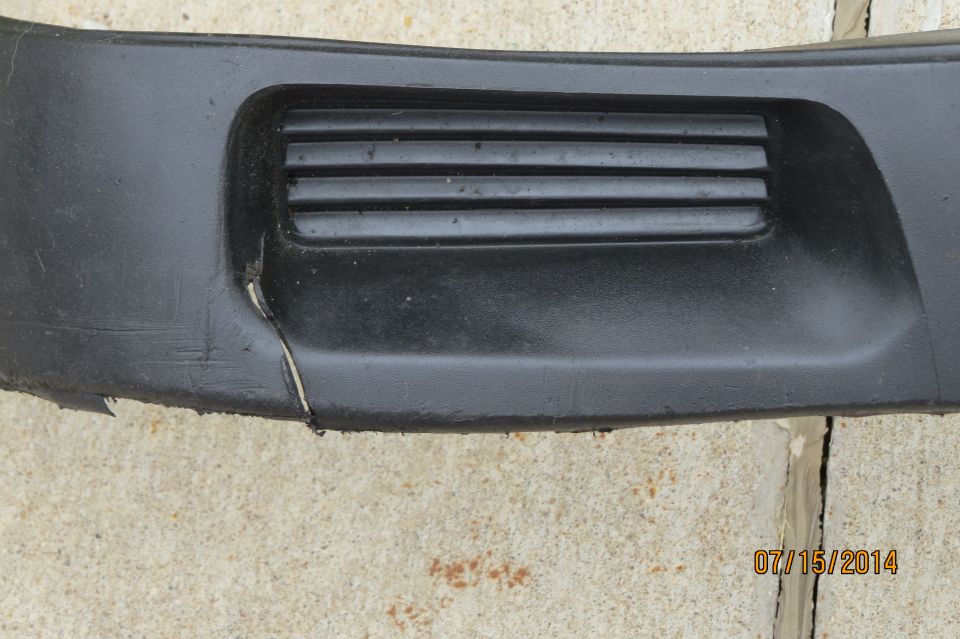 Close-up of a black car bumper with a horizontal vent and a crack