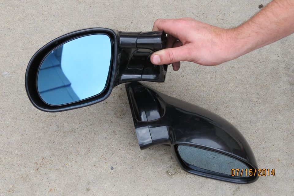 Two black car side mirrors with blue tinted glass, one held by a hand