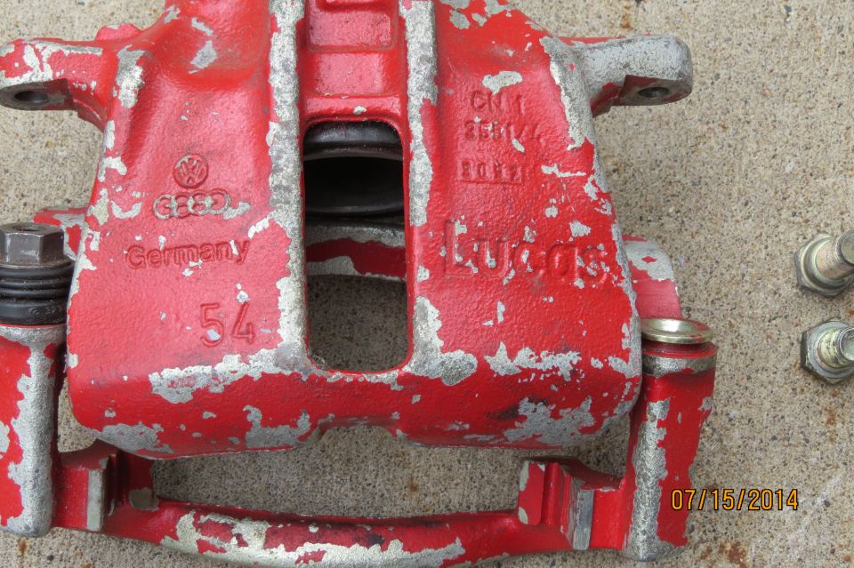 Red brake caliper with "VW" logo and "Germany" text, showing wear