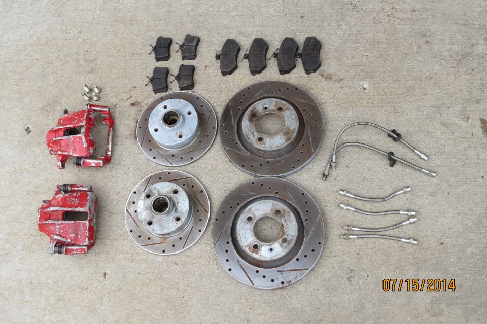 Red brake calipers, rotors, and brake pads laid out on concrete
