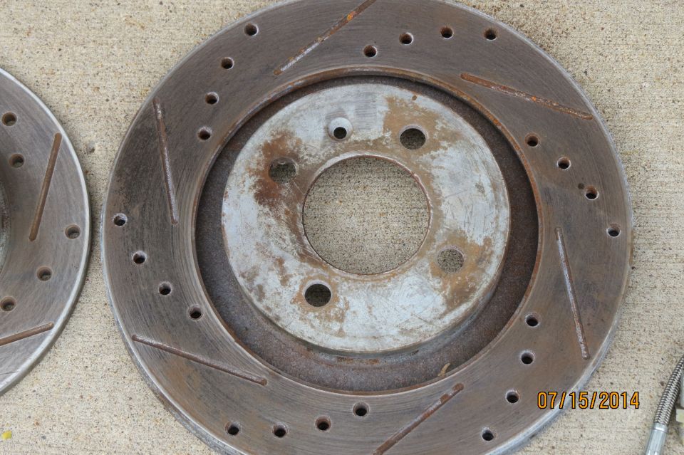Slotted and drilled brake rotor with rust and wear marks. Date stamp '07/15/2014' and 'SUPERMOTORS.NET' visible