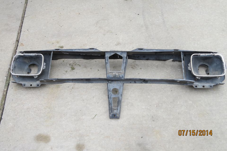Gray metal front grille support with two square headlight openings and chrome trim
