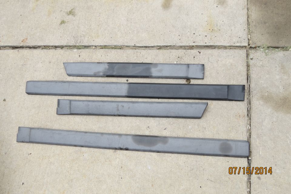 Four gray car door sill trim pieces laid out on concrete