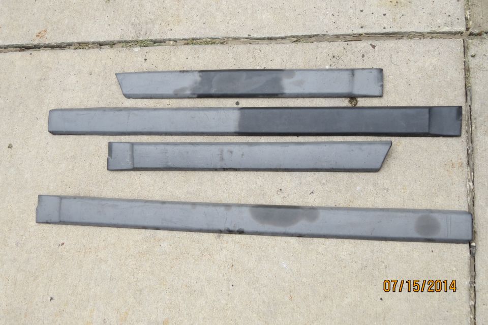Four gray car door trim pieces laid out on concrete. One piece has a diagonal cut at the end