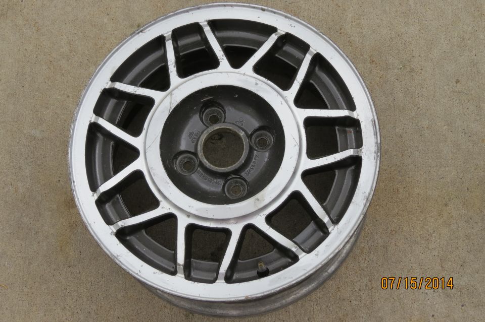 Aluminum alloy wheel with a multi-spoke design, silver and black finish, on a concrete surface