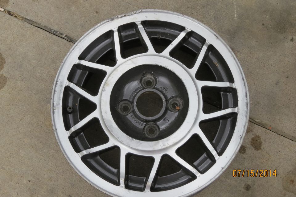 alloy wheel with 10 spokes, silver rim, black inserts, and 4 lug nuts visible