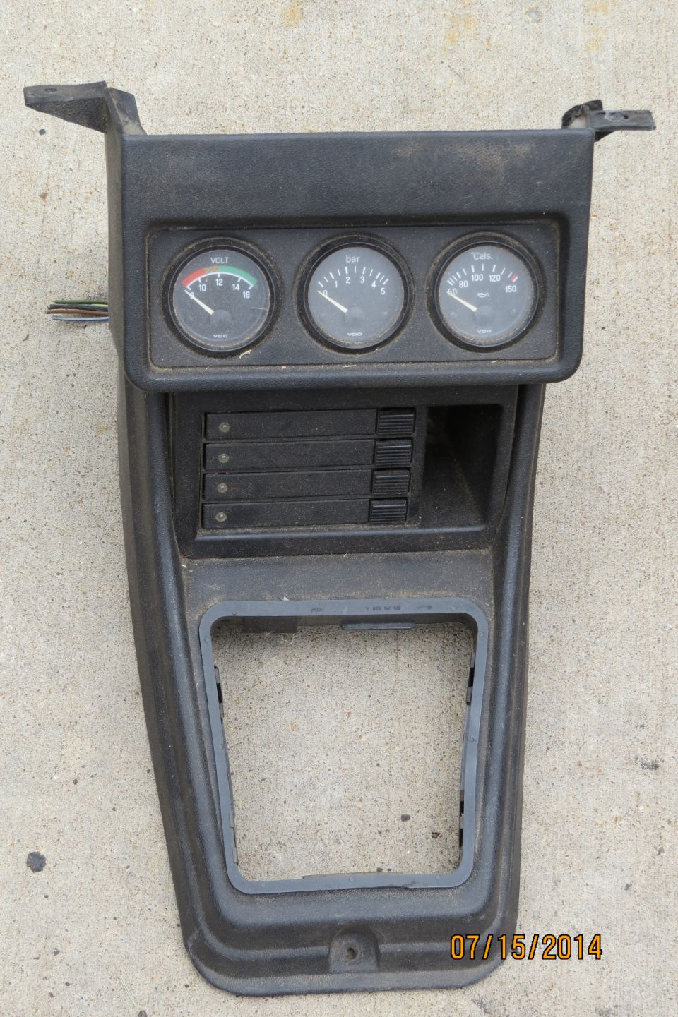 Black plastic dashboard trim with three gauges: voltage, RPM, and speedometer. Also has slots for cassette tapes