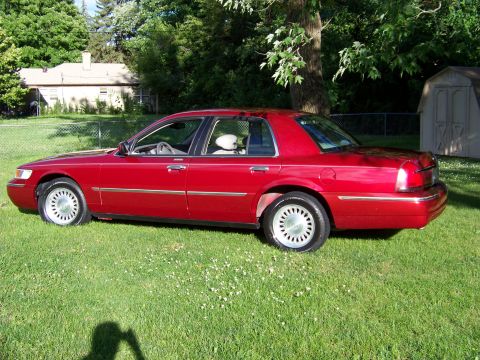 1999 Mercury Grand Marquis - Red 1999 Mercury Grand Marquis parked on grass in front of a house and shed.