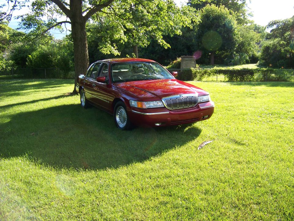 1999 Mercury Grand Marquis 3q-front view, red sedan parked on grass