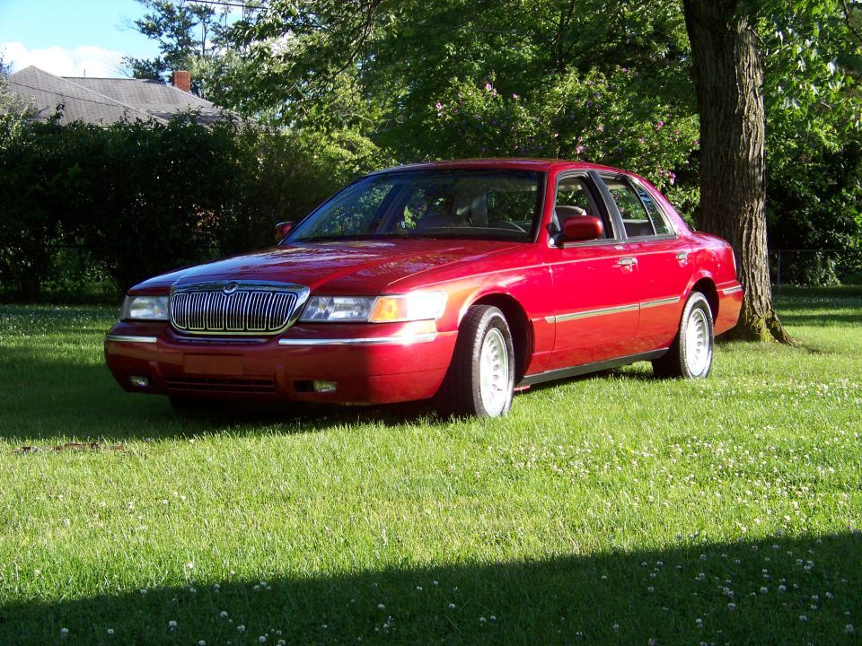 Red 1999 Mercury Grand Marquis parked on grass, 3q-front view