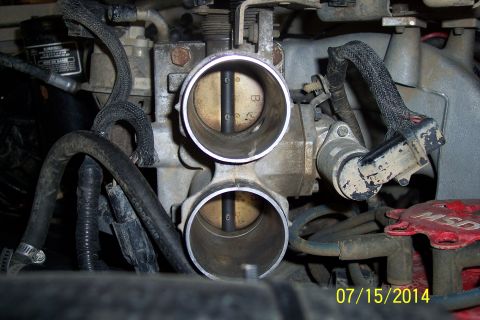 1990 Ford Bronco - Close-up view of an engine's throttle body assembly, showing the dual intake ports and internal components.