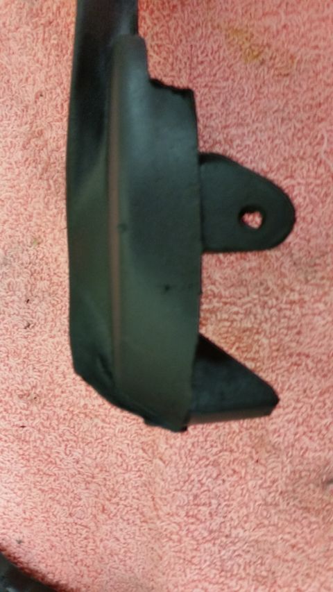 1973 Chevrolet Camaro - A black plastic automotive part with a mounting tab is shown against a pink textured background.
