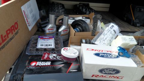 1972 Ford Ranchero - Various automotive parts are organized in the bed of a vehicle, including engine components and Ford Racing branded items.
