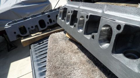 1972 Ford Ranchero - Two engine cylinder heads are shown, one in sharp focus, resting on a truck bed with a carpeted surface.