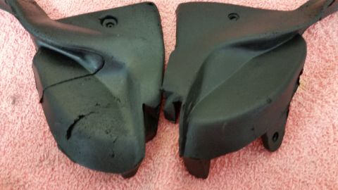1973 Chevrolet Camaro - Two black plastic automotive parts are shown on a pink textured surface.