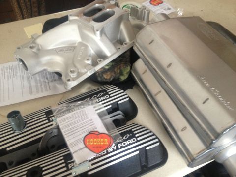 1979 Ford Bronco - Various engine performance parts are laid out on a table, including an intake manifold and valve covers.