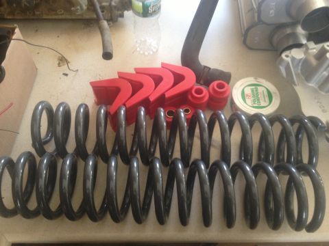 1979 Ford Bronco - Collection of suspension components including coil springs and red polyurethane bushings, along with a container of polishing compound.