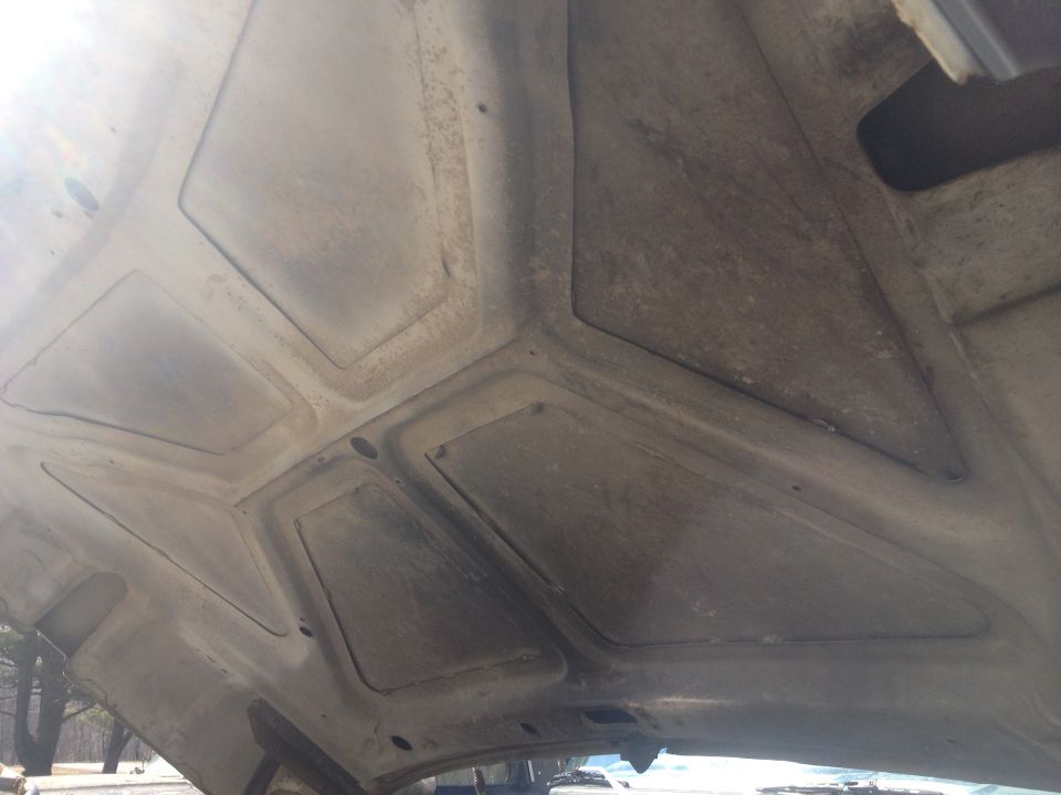 Underside of a dusty vehicle hood with reinforced panels