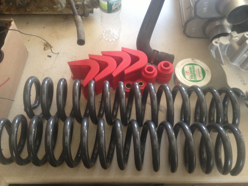 Coil springs, red polyurethane bushings, and a can of polishing compound on a surface