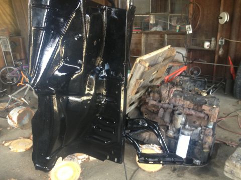 Black painted vehicle fender and rusty engine block in a garage