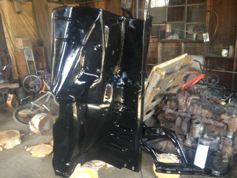 Black painted vehicle floor pan in a workshop setting