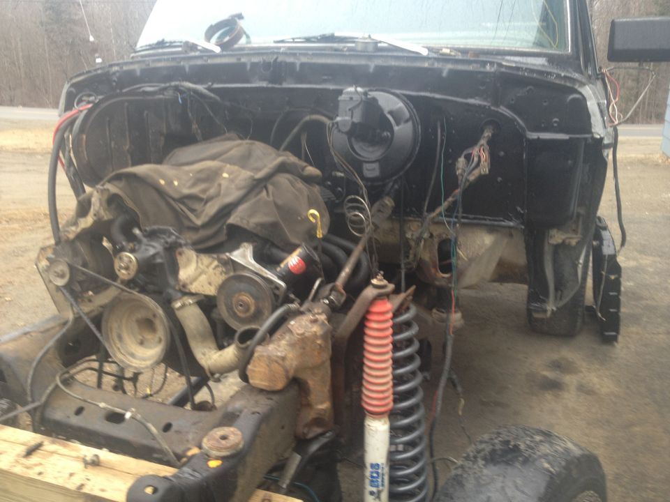 Black 1979 Ford Bronco engine bay with engine removed, showing exposed chassis and suspension components