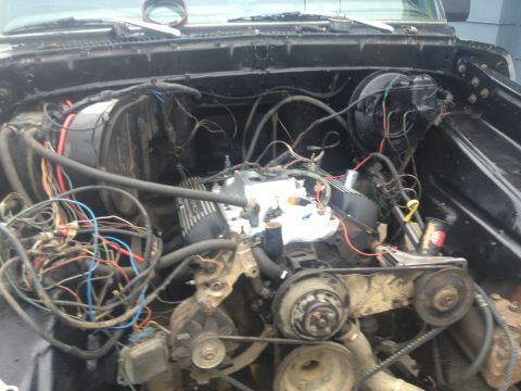 Engine bay with exposed wires and engine components. Some parts appear to be covered in foil