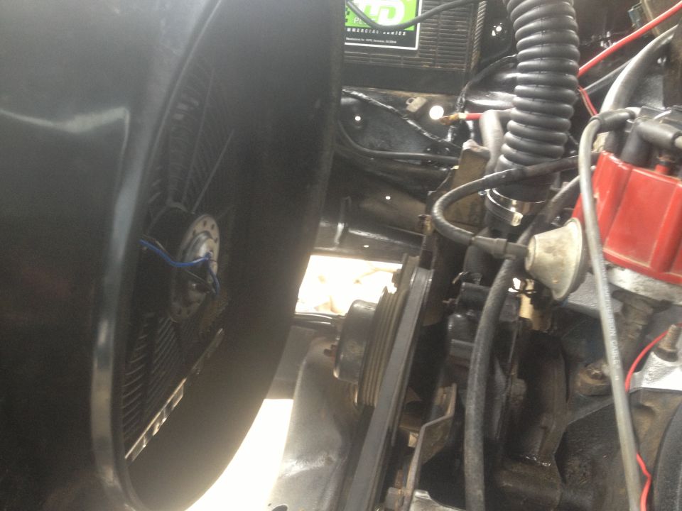 Close-up of engine bay showing fan, belts, distributor, and hoses