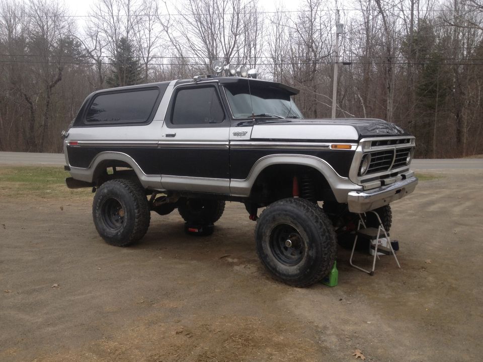 Lifted 1978 Ford Bronco, two-tone black and silver paint, aftermarket wheels, off-road lights on visor