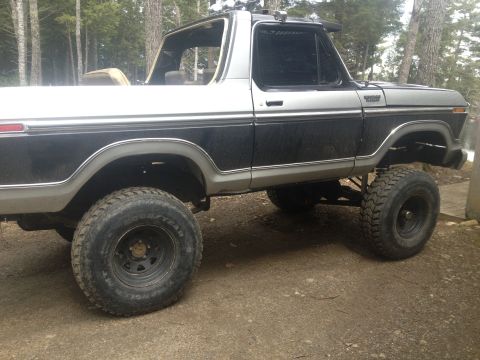 Two-tone black and silver 1978 Ford Bronco with lifted suspension and off-road tires, viewed from the side