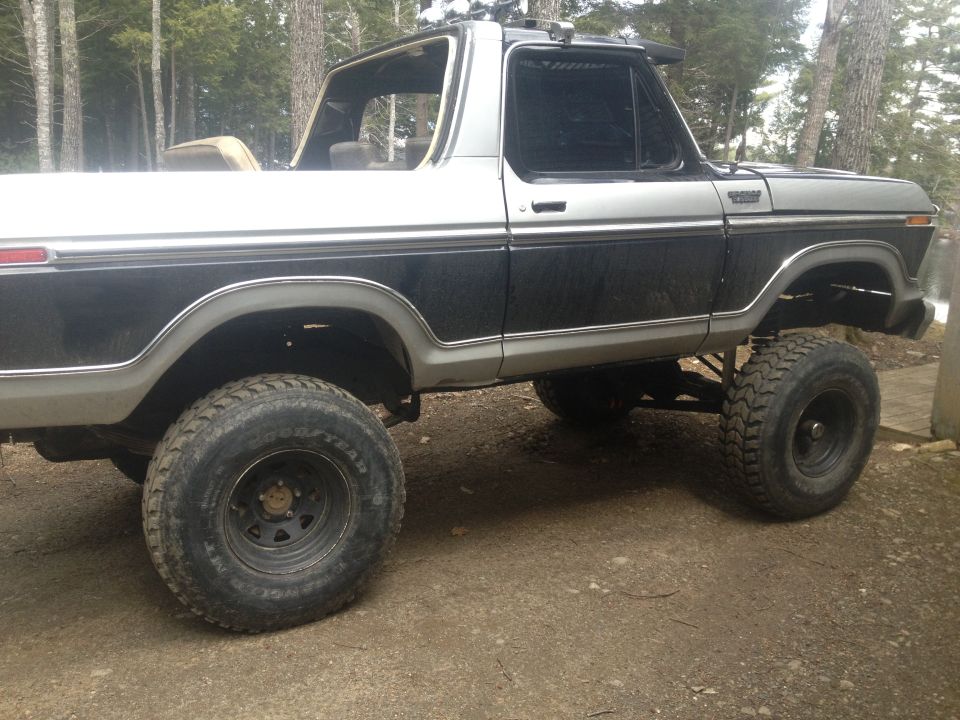 Two-tone black and silver 1978 Ford Bronco with lifted suspension and off-road tires, viewed from the side