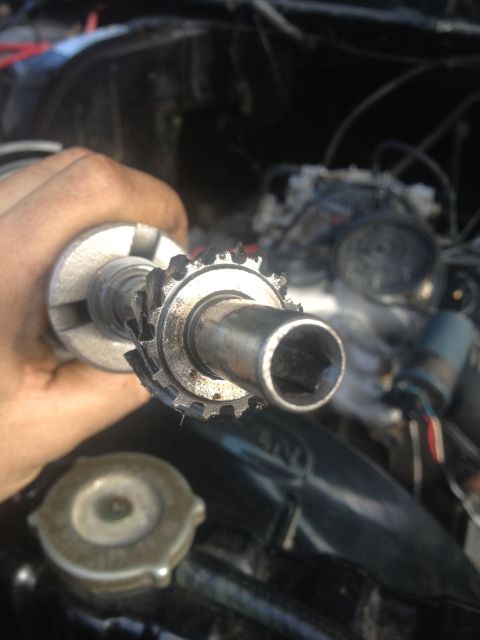 Distributor rotor held in hand, with engine components in background