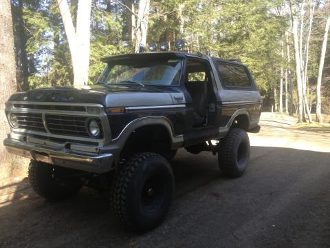 Lifted black and silver Ford Bronco with open driver's door parked outdoors