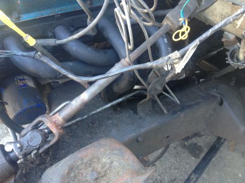 Engine bay with exhaust manifold, hoses, and drive shaft visible