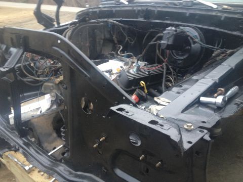 Vehicle engine bay with engine removed, showing frame and wiring. Tools are on the right