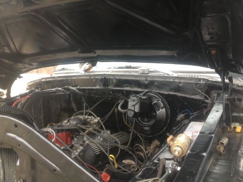 Black engine bay with exposed engine components, wiring, and brake master cylinder