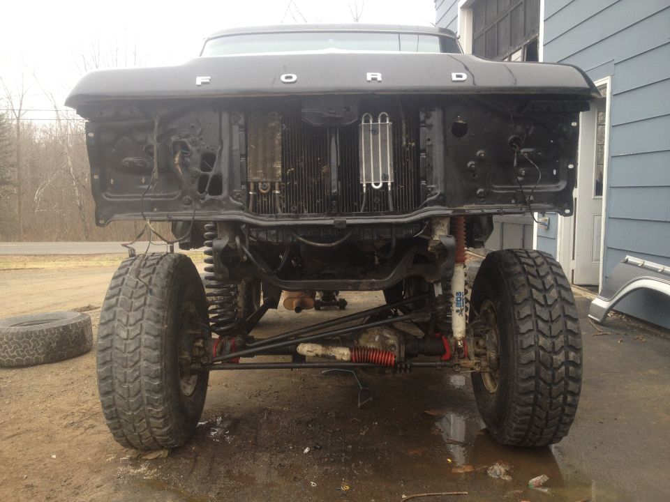 Front of a lifted Ford truck with grille removed, showing radiator and suspension components