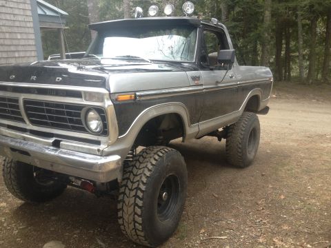 Two-tone black and silver Ford Bronco with off-road tires and roof-mounted lights