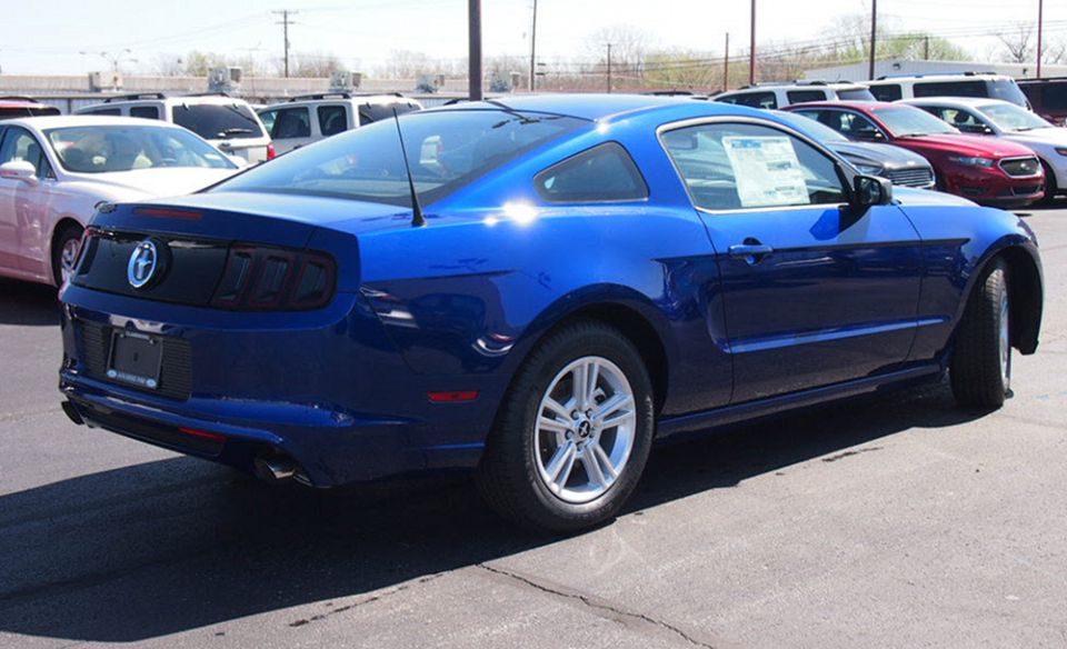 Blue late-model Ford Mustang coupe, rear three-quarter view, parked on a dealer lot