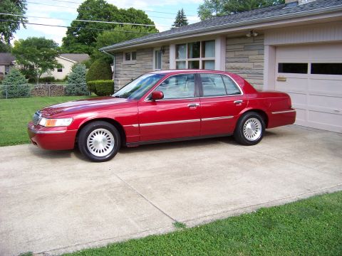 1999 Mercury Grand Marquis - Red 1999 Mercury Grand Marquis parked in a suburban driveway next to a garage.