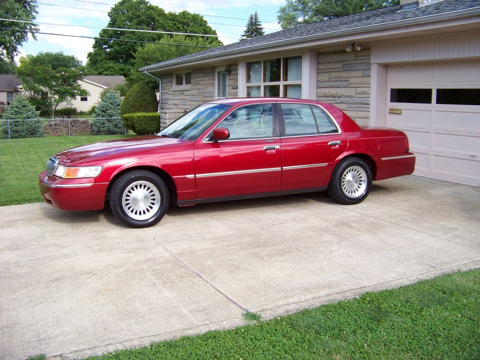 1999 Mercury Grand Marquis parked on concrete driveway in front of a house with a garage