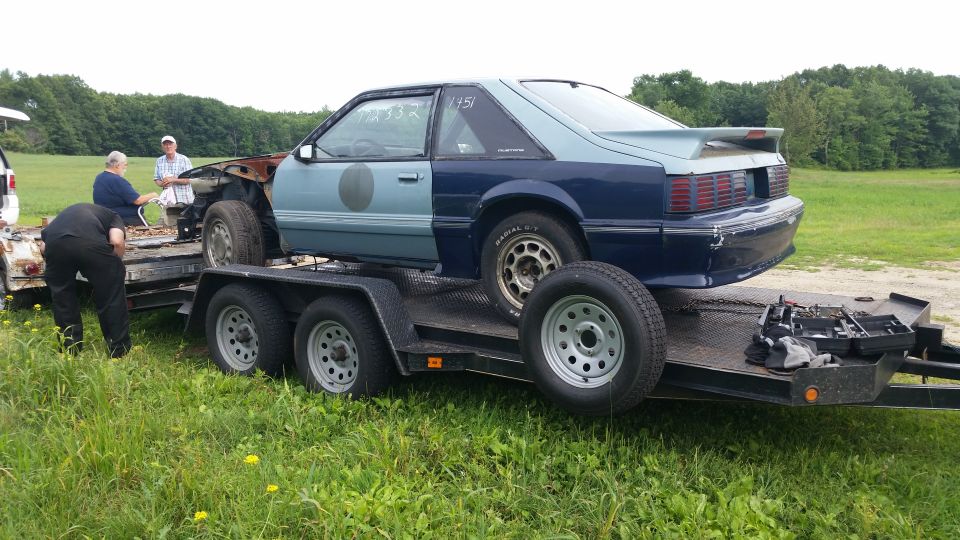 1991 Ford Mustang on a trailer, front end is light blue, rear is dark blue, some rust visible