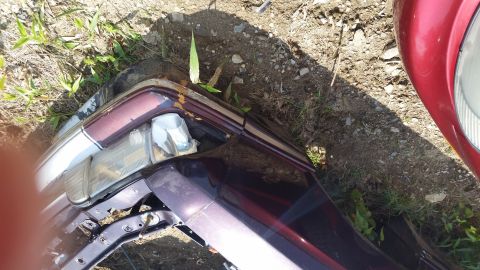 1991 Ford LTD Crown Victoria - A damaged car bumper and headlight assembly lie on the ground next to another vehicle.