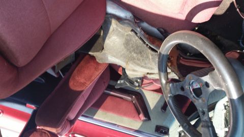 1991 Ford LTD Crown Victoria - The interior of a red car shows maroon seats and a dashboard in disrepair.