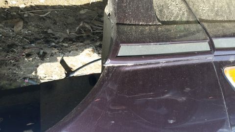 1991 Ford LTD Crown Victoria - Detail of a car's fender and trim, showing some wear and tear.