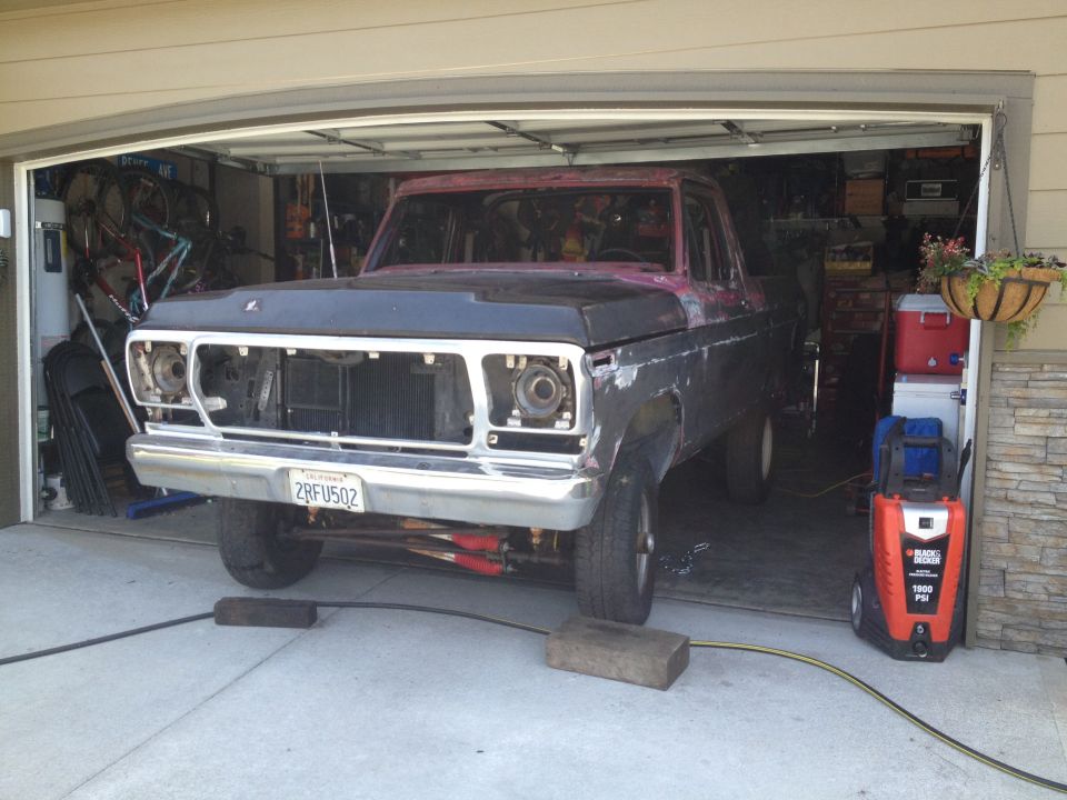 Truck front end in garage, missing headlights and grille. California license plate 2RFU502 visible