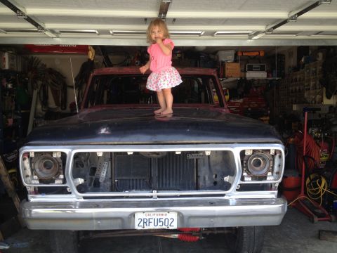 1978 Ford Bronco - A young girl stands on the hood of a 1978 Ford Bronco in a garage.