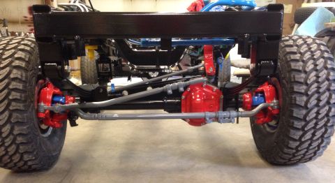 1993 Ford Bronco - Close-up view of the front axle assembly, red brake calipers and a red differential housing.
